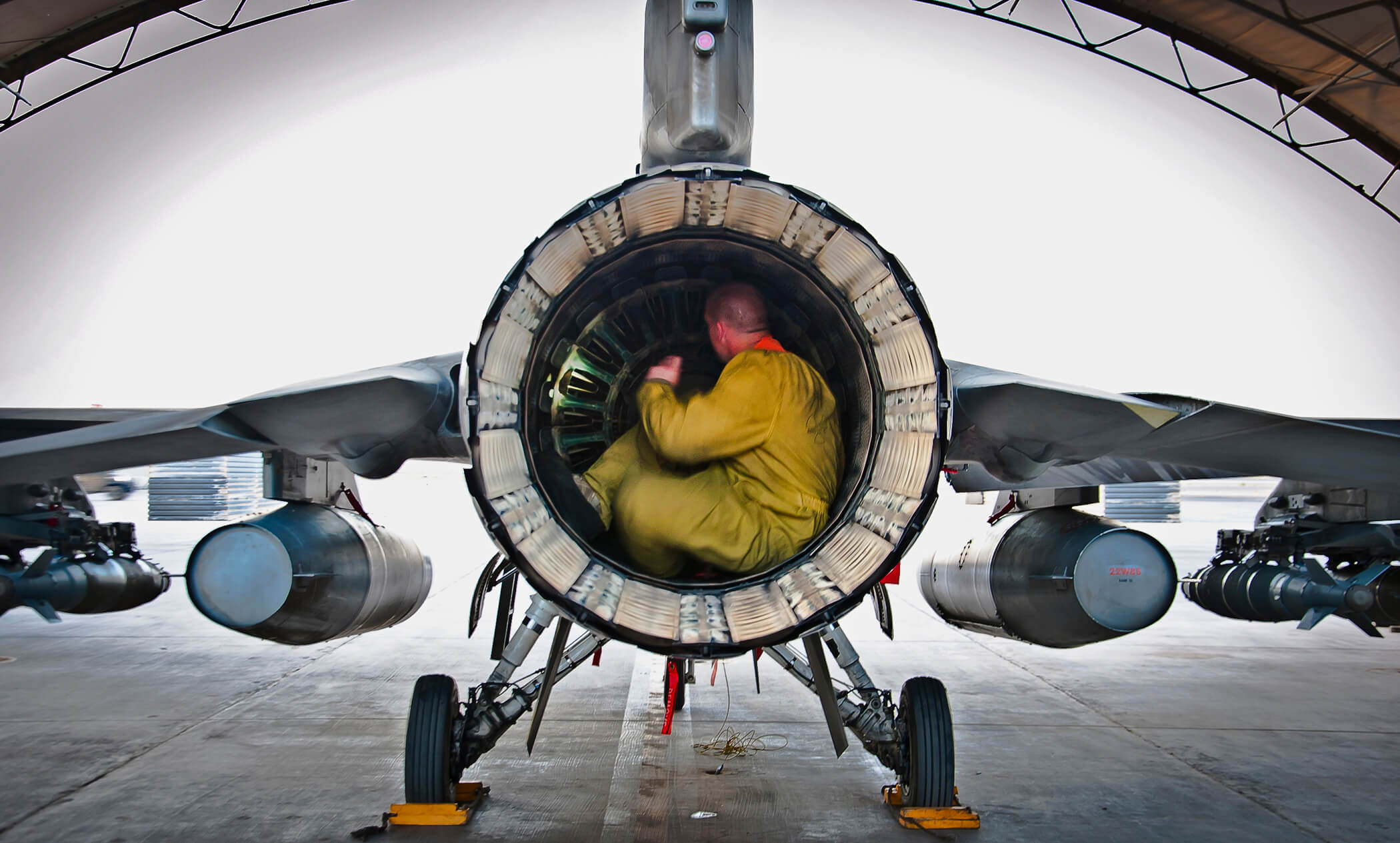 airman inspecting engine of fighter aircraft